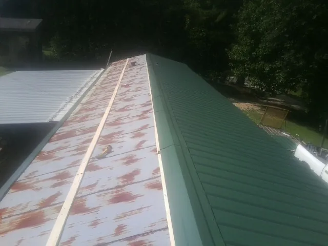 Old rusted panels beside newly installed green metal roofing — Wind Damage Roof Repair by Roofing Brothers in Balaton