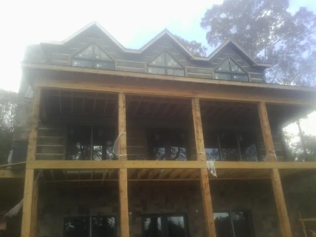 Dormers and porch framing on a large log home under construction — Roof Coating work by our crew in Balaton