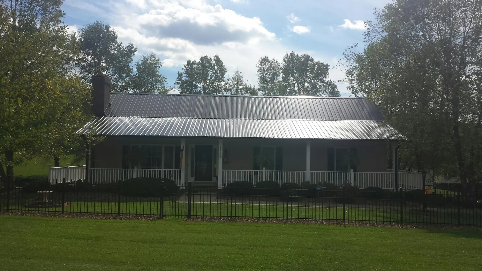 Gray metal roof on a brick ranch with a full width front porch — Gutter Guard Installation work by our crew in Balaton