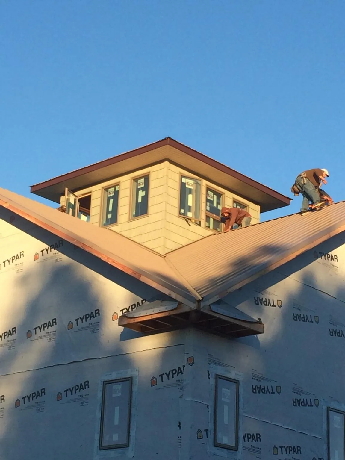Roofers working around a rooftop cupola on a new metal roof at sunset — Roof Waterproofing in Balaton by Roofing Brothers